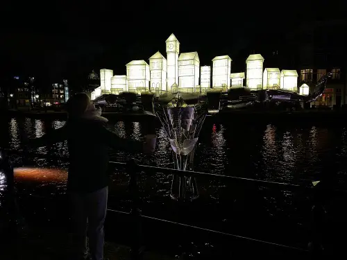 A statue with light from Amsterdam canal houses