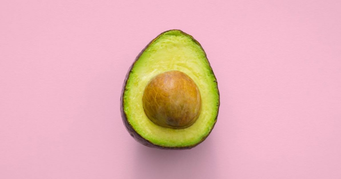 Half an avocado with a pink background