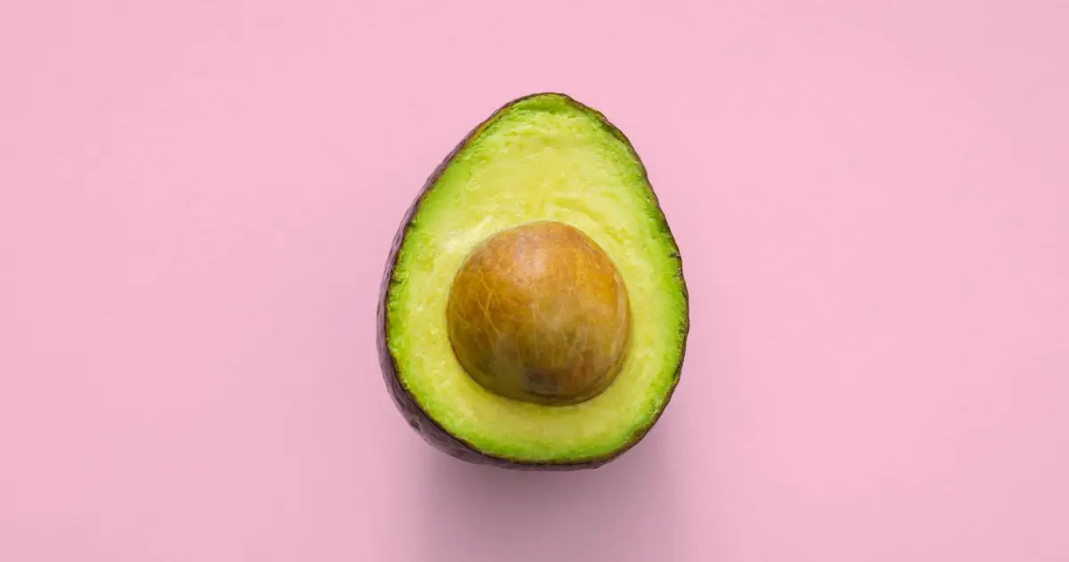 Half an avocado with a pink background