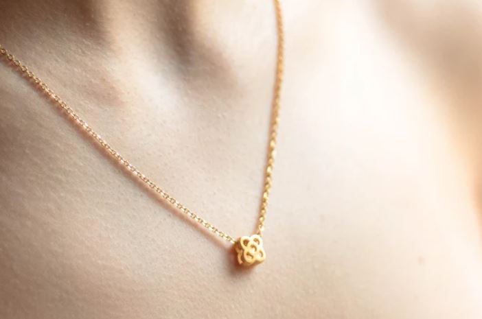 A golden necklace with a tile pattern pendant