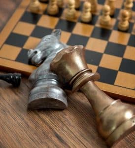 Two pieces of solid chocolate in the shape of a chess queen and horse on a chessboard