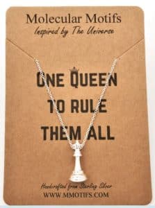 A necklace with a pendant of a chess queen pice and the text "one queen to rule them all"