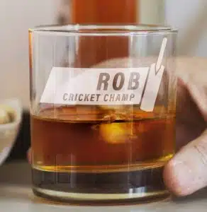 A whiskey glass with a personalization and a cricket bat