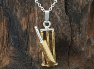 A necklace with a golden pendant shaped like a cricket bat
