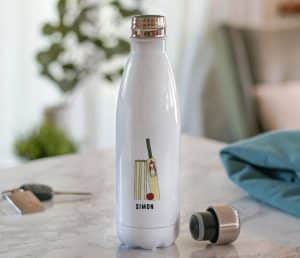 A white water bottle with a name and cricket ball, and bat