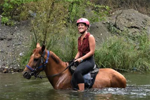 Woman riding on the back of a horse in water
