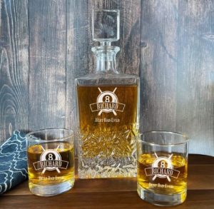 A whiskey decanter with glasses with pool balls etched and a name