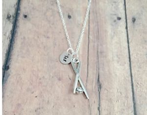 A silver necklace with a pendant of two cues and a pool ball