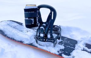 A snowboard with a binder to hold a can of beer