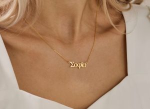 A woman wearing a necklace with a name written in Greek letters