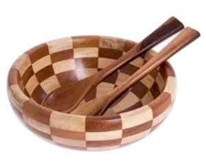 A wooden salad bowl with spoons and a checker pattern