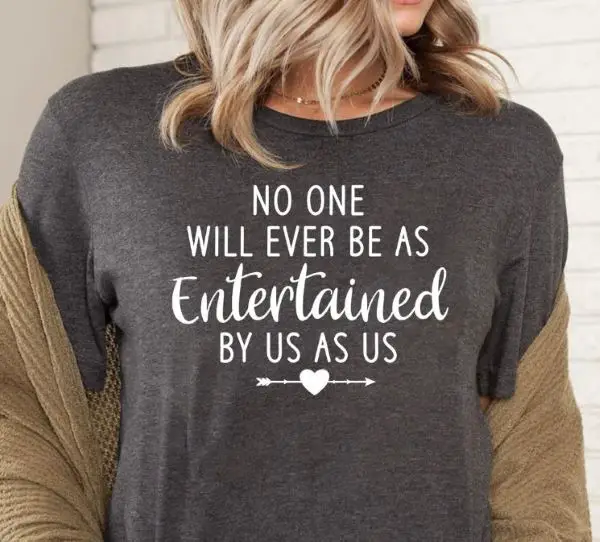 Woman wearing a grey t-shirt with quote: "no one will ever be as entertained by us as us"