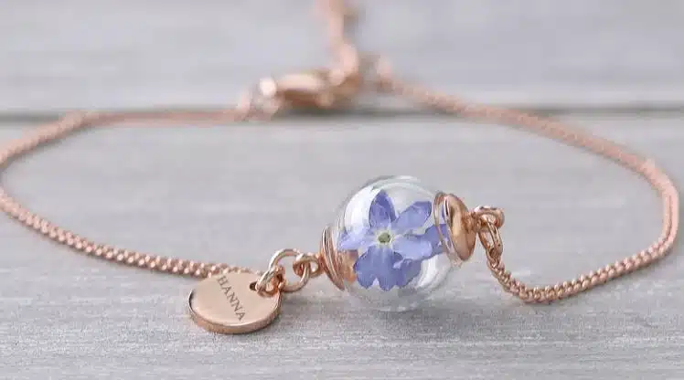 A bronze bracelet with a charm of a dried forget me not flower