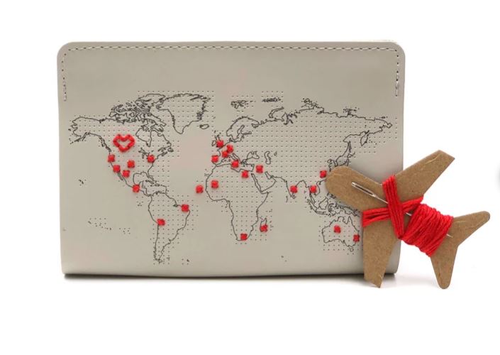 A passport cover iwth the world map and a needle and thread