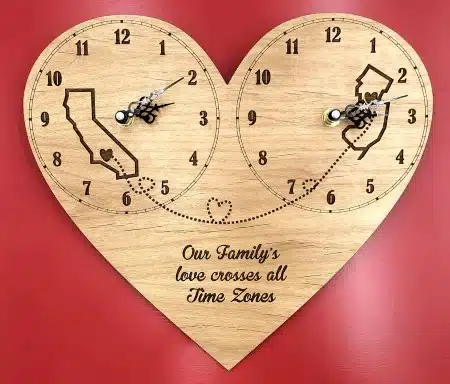 A wall clock shaped like a heart and with two clocks of different time zones
