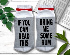 A pair of socks with a funny text at the bottom "if you can read this, bring me some rum"