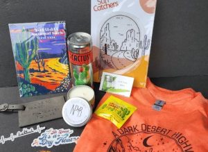 Various items such as shirts, candle, can, luggage tag, and book on a table