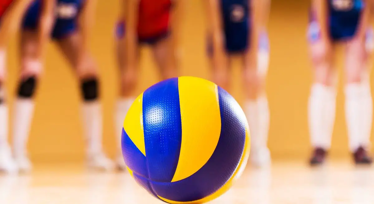 A volleyball in the middle with vague shadows of volleyball players in the background